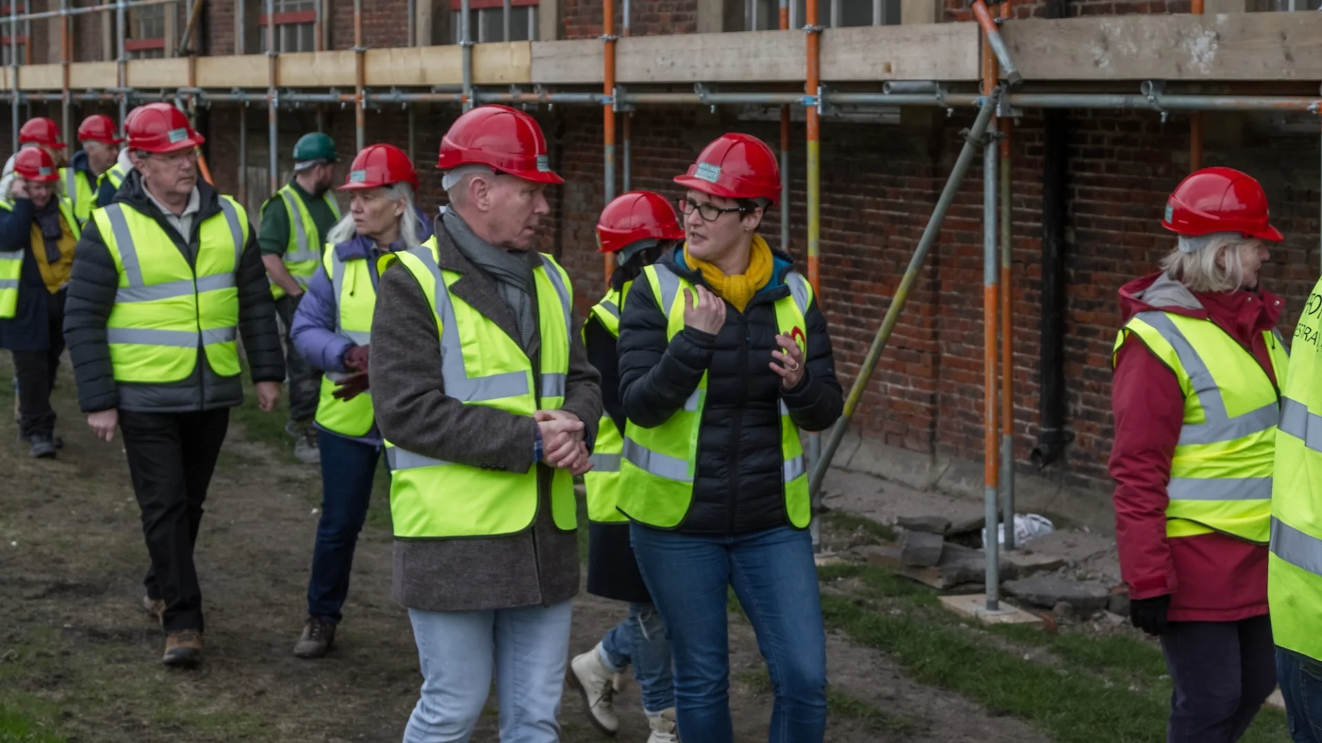 Tour around church with scaffolding, all those on the tour wear red hard hats