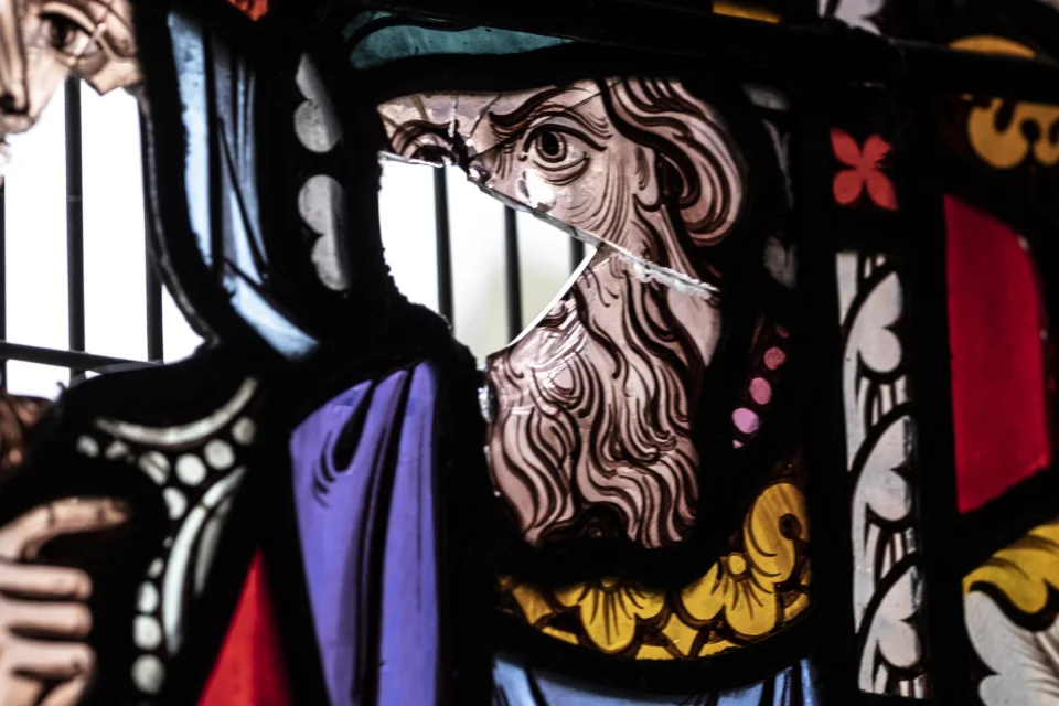 A stunning stained glass window that has been broken in several places.