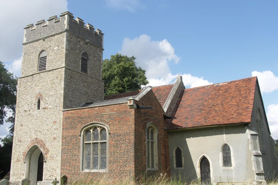 Exterior of flint-towered St Mary's church with brick south chapel.