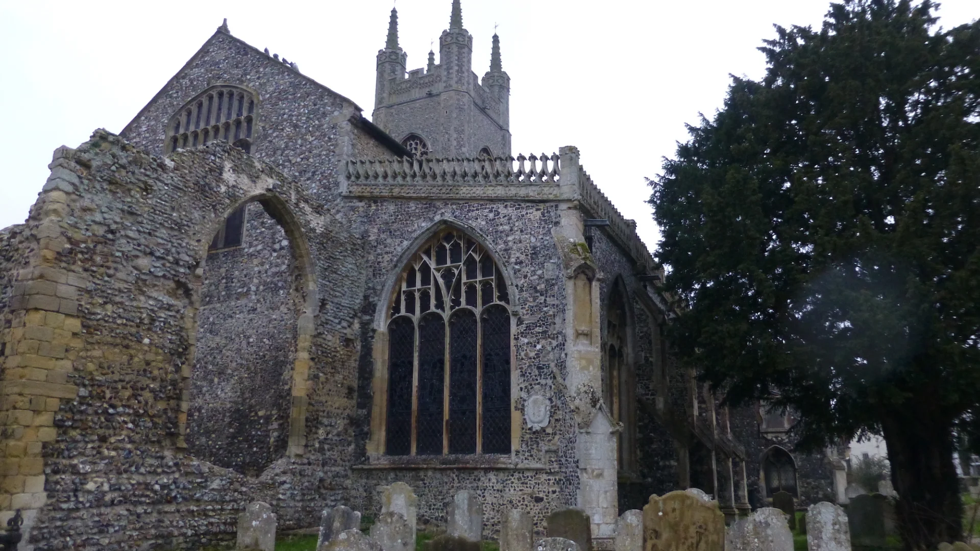 Remains of Priory Buildings showing half destroyed wall with graveyard around