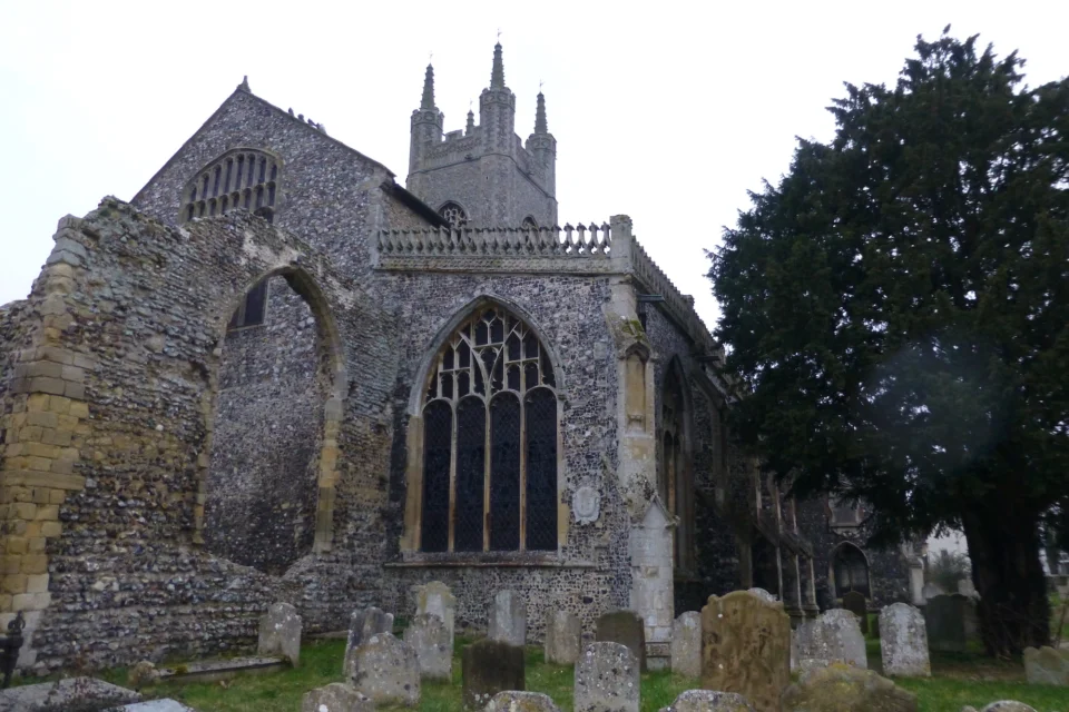 Remains of Priory Buildings showing half destroyed wall with graveyard around