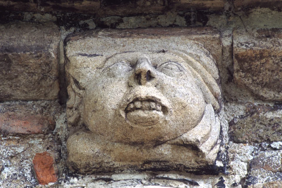 Corbel possibly C14th re-set above east window arch during the C18th restoration shows a human face with large exposed teeth