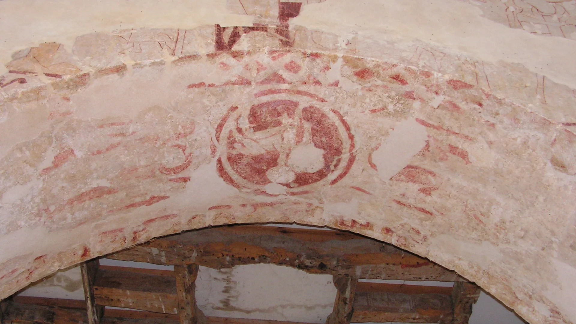red wall paintings people and zig zag designs on an archway
