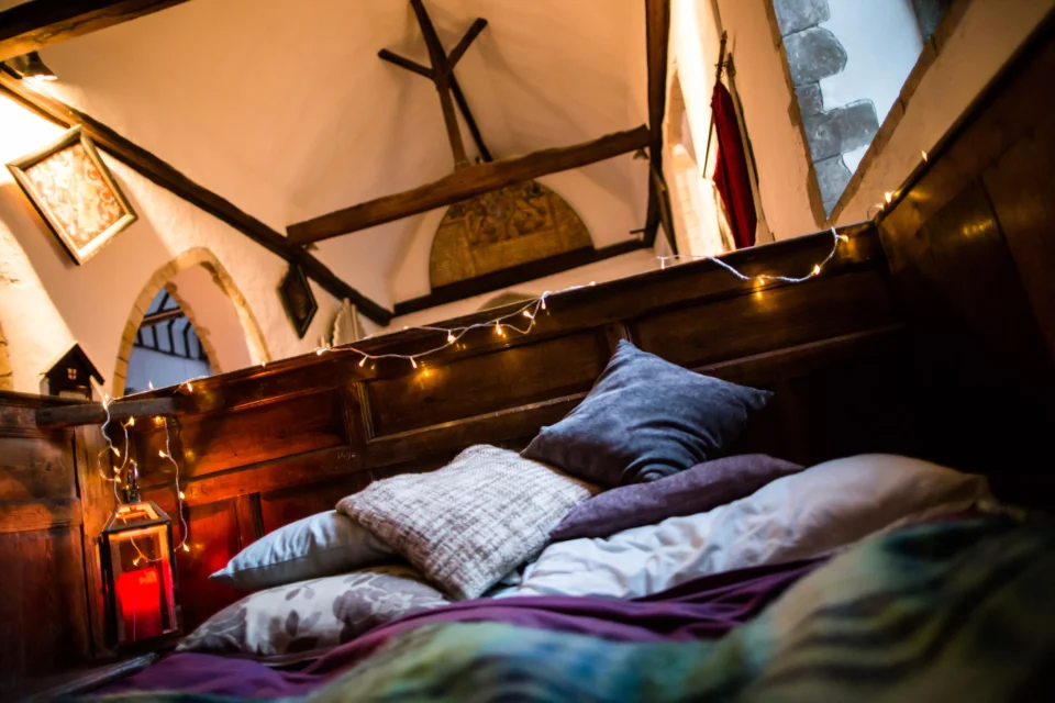 Bed among pews with fairy lights and lanterns