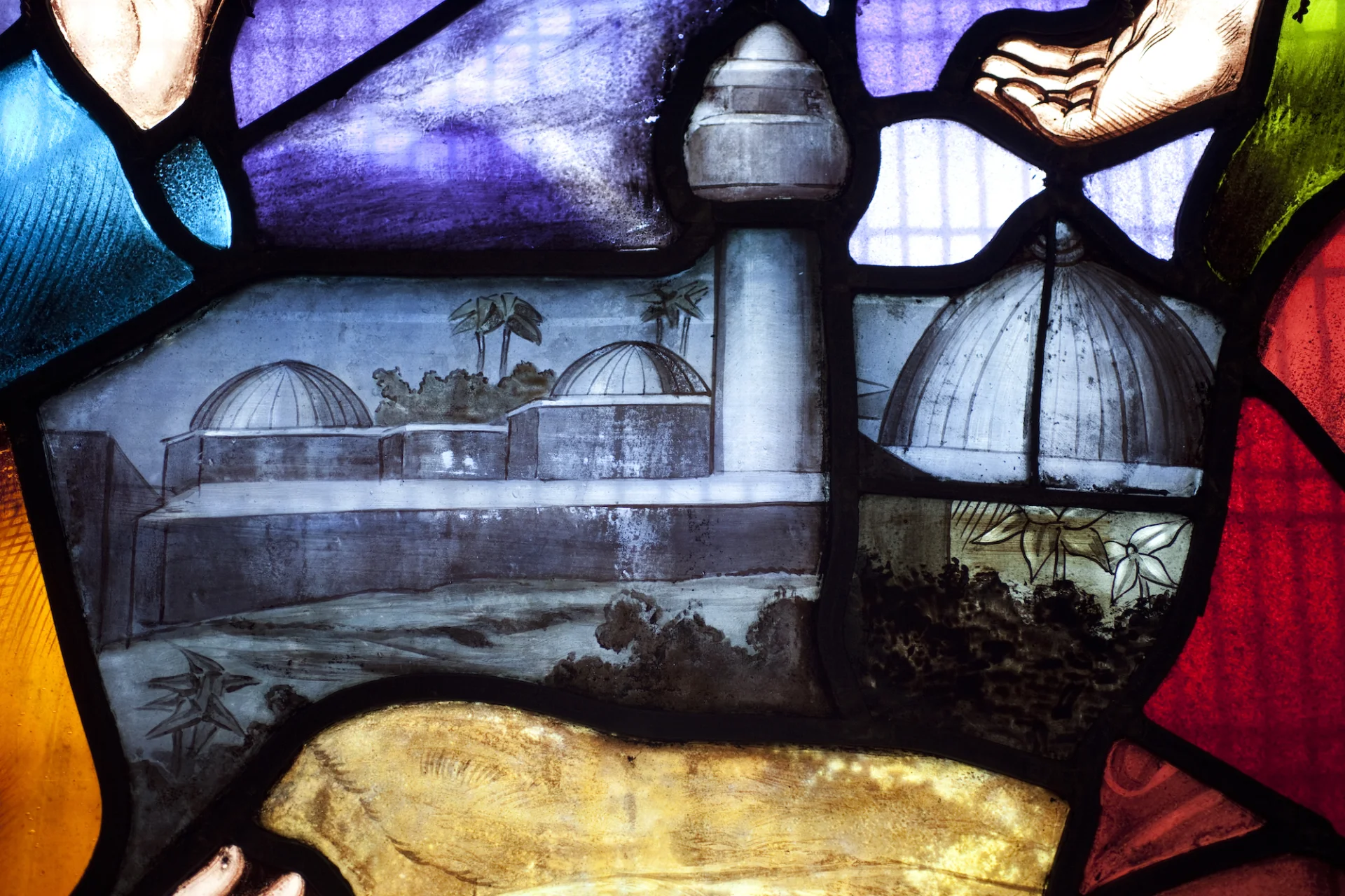 Close up of stained glass domed roof building in grey and hands in green and red