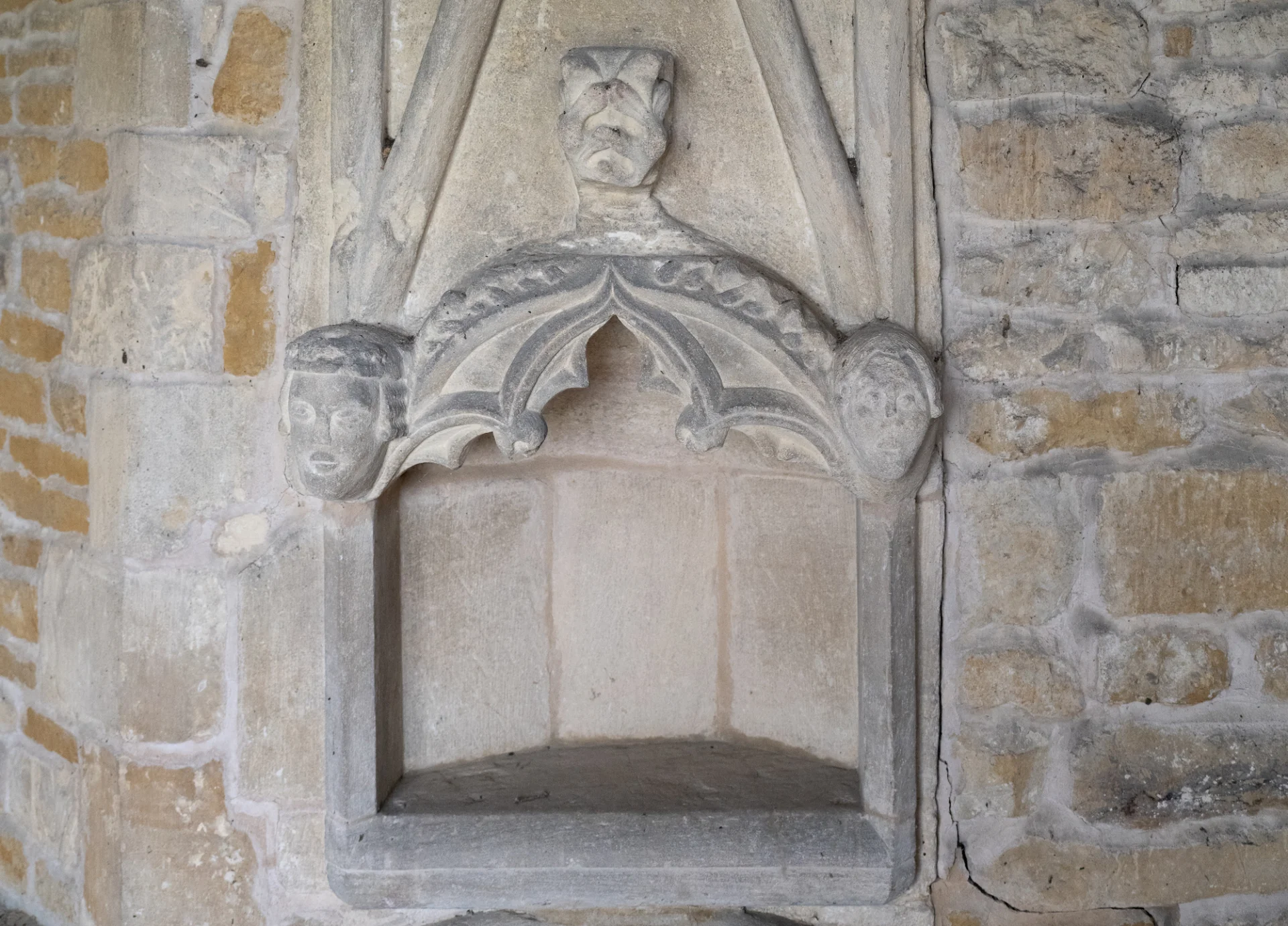 Drop-sill Sedilia ( a ceremonial seat) indented into the stone wall with carved faces around the top.