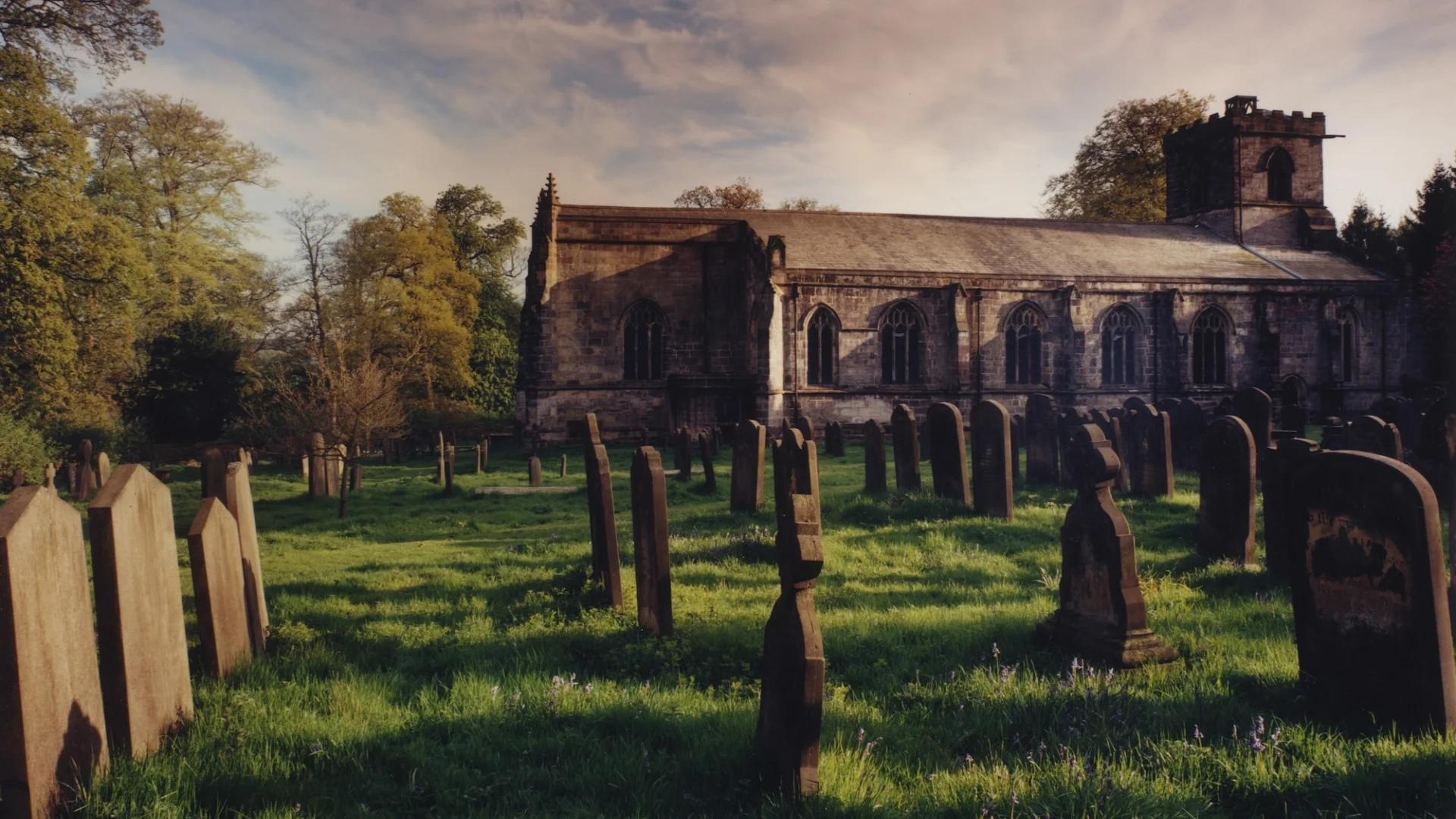 church exterior with long nave, photographed through the graveyard