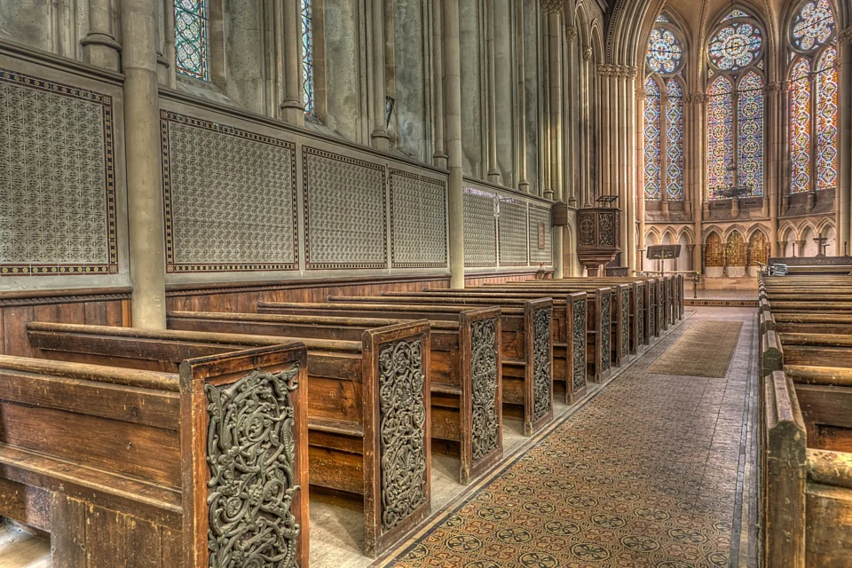 The pews of St Mary's Church are decorated with cast iron scrollwork and foliage. Ornate tiles along the middle of the church lead to arched windows containing small pieces of clear red, blue and green glass arranged in geometrical patterns.