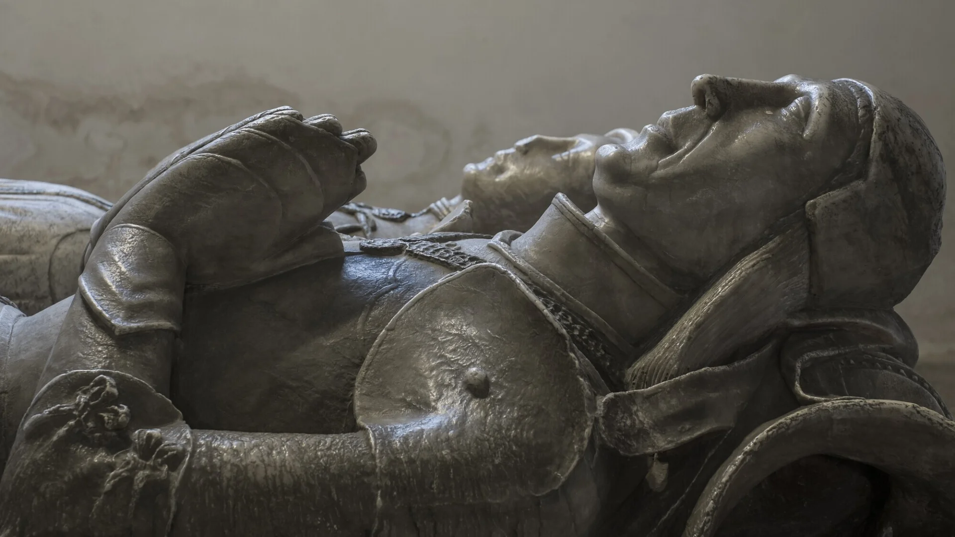 Stone carving monument of Sir John Curzon in full armour with his wife and their two dogs.
