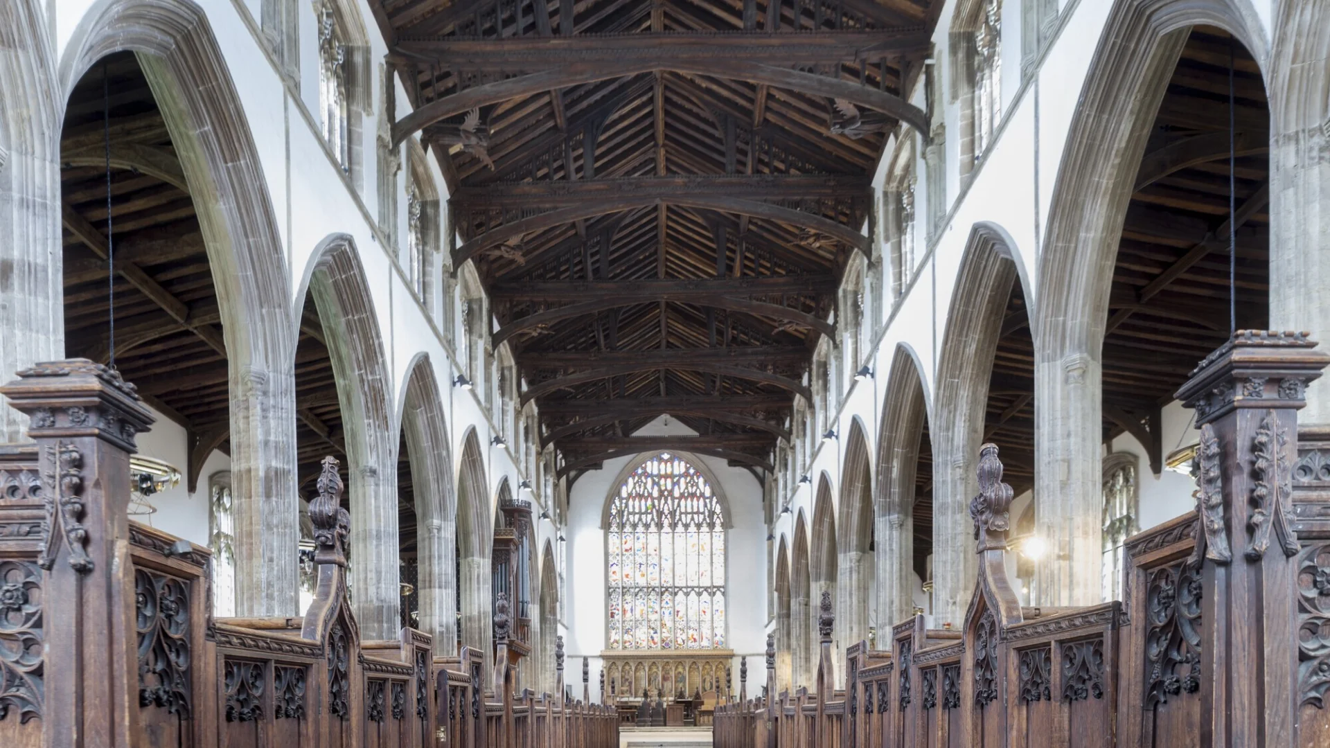 Atmospheric view of the interior with its stone columns and large stained glass window above the altar