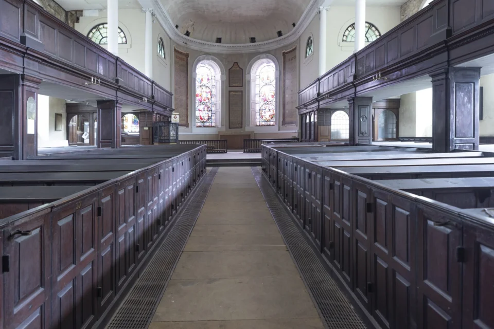 View of the large interior with white walls and wood pews