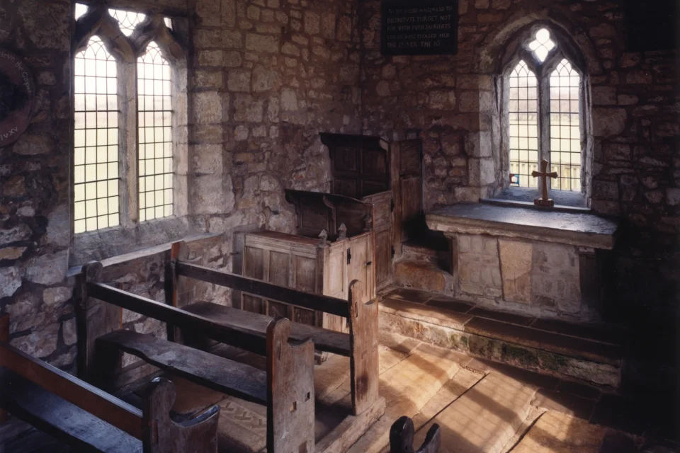small interior shot of dark church with a rustic wooden floor, pulpit, clerk's pew,