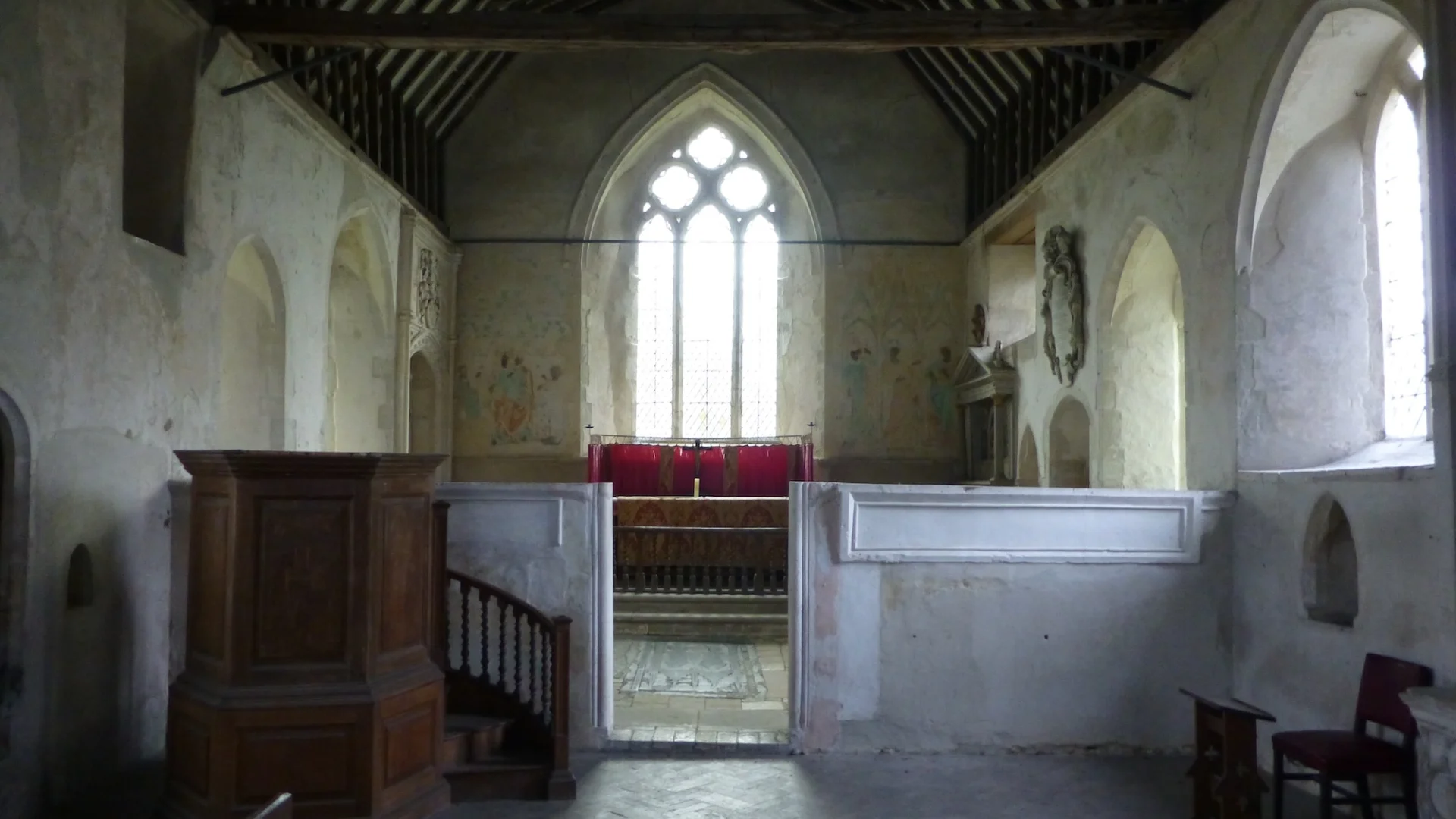 Interior of small church with large clear glass window behind altar