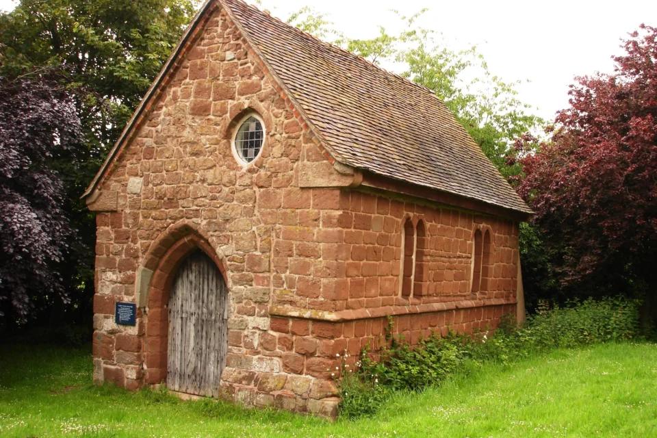 red stone small building, the surviving south aisle of a medieval church.