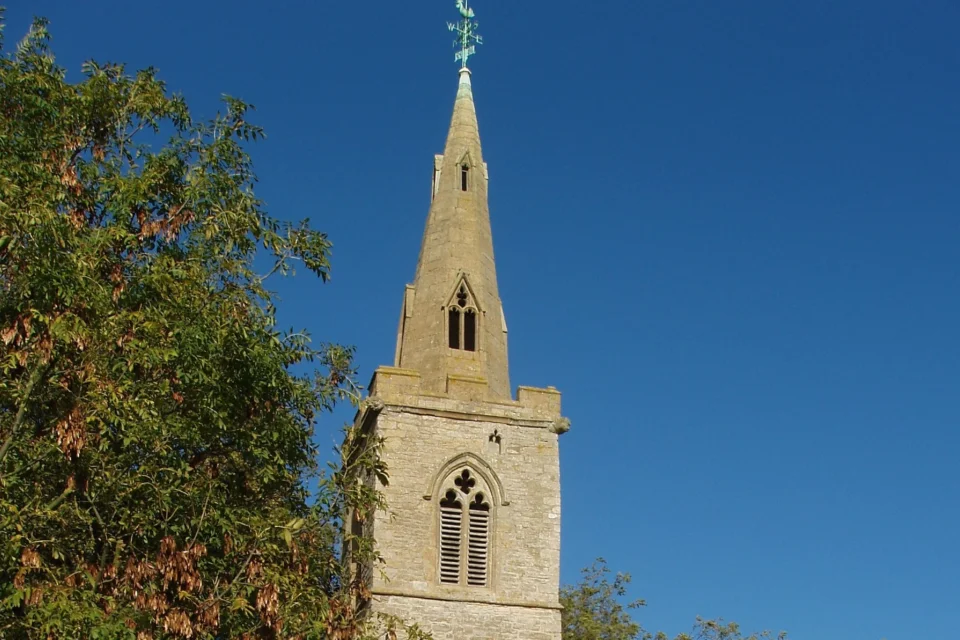 Fourteenth century steeple with blue weathervane showing north, south, east and west.