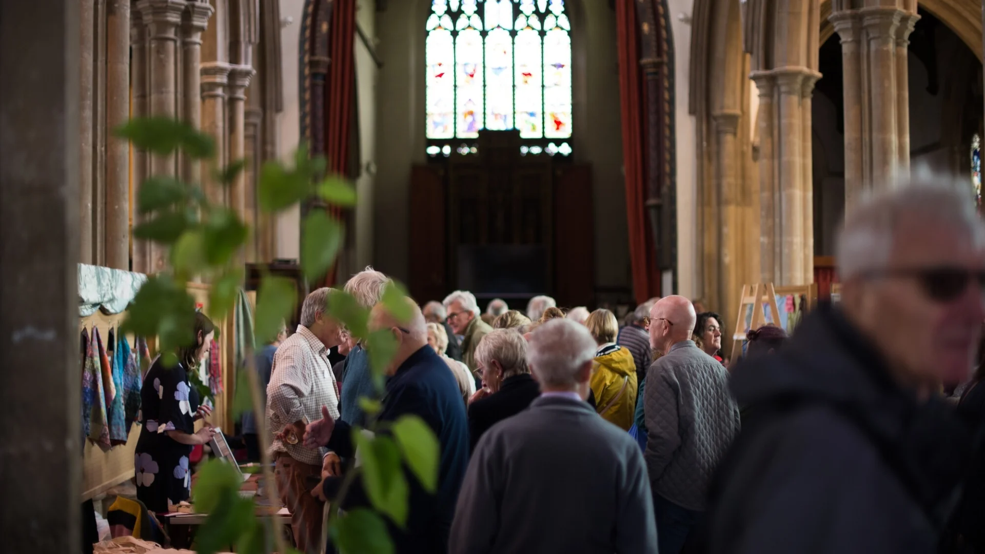 large groups of people look at stands where art and objects are being sold within the nave