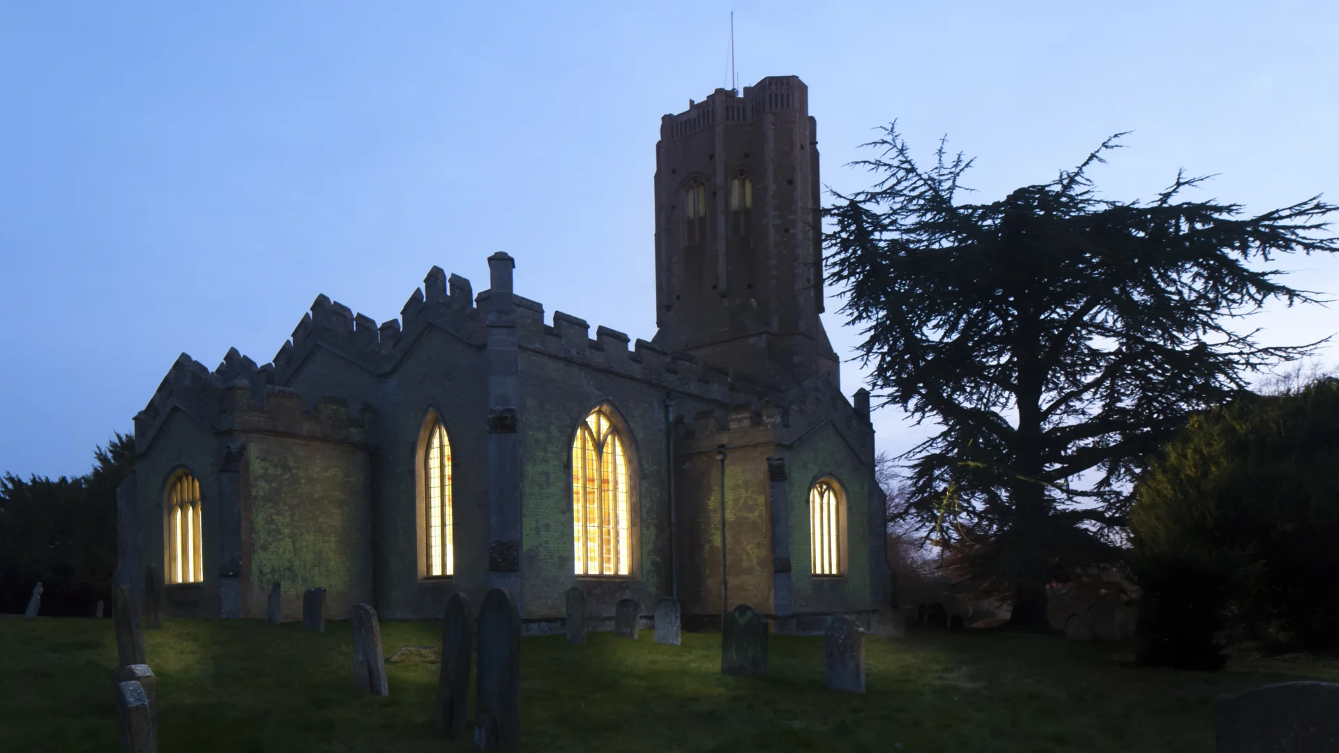 View of the church in early evening with the lights pouring out the windows