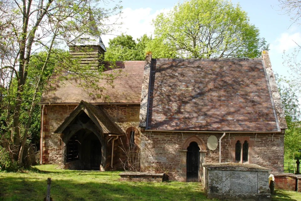 Exterior image of the stone and brick built church among some trees