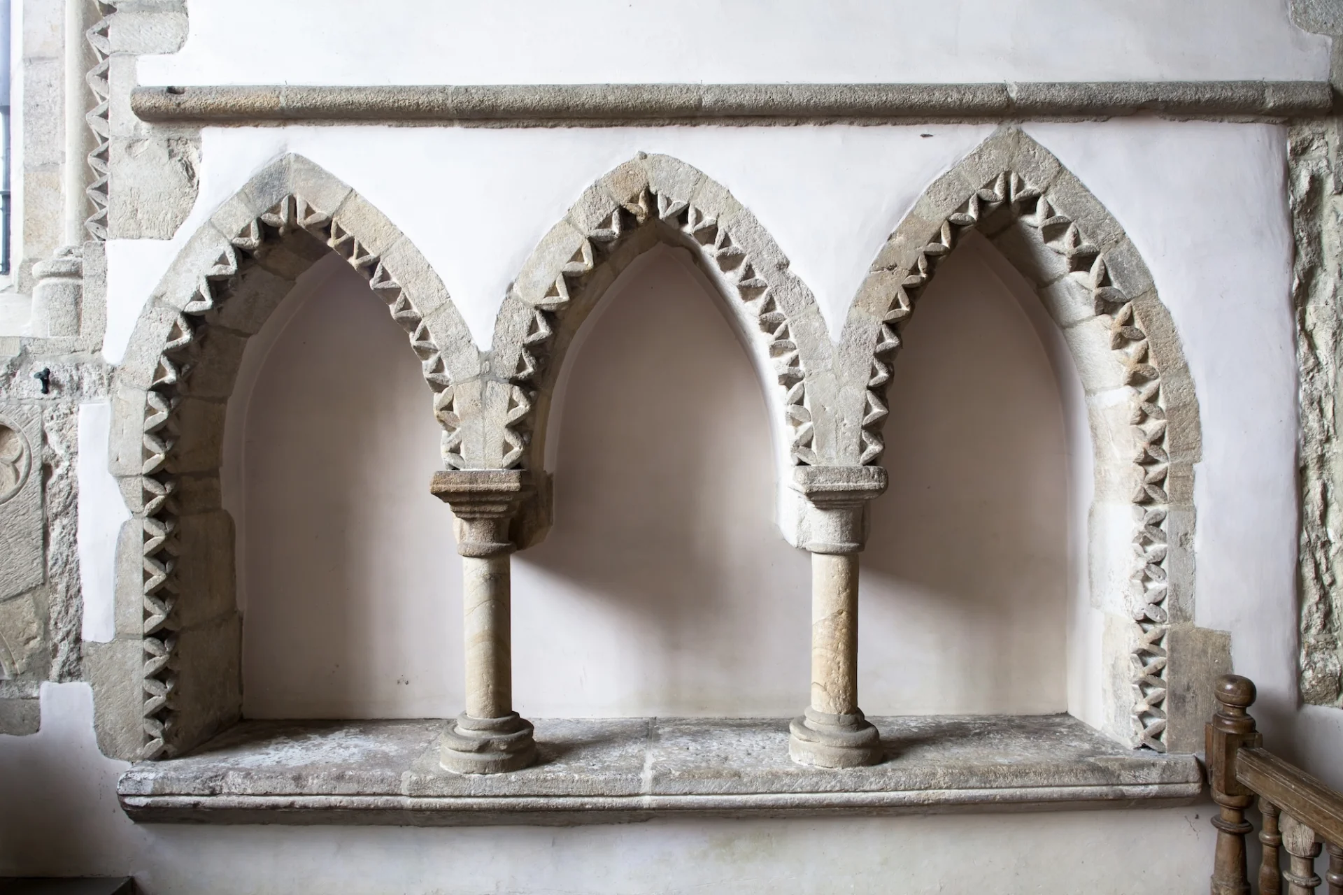 three stone arched niches with a geometric reoccurring triangular design following the archway
