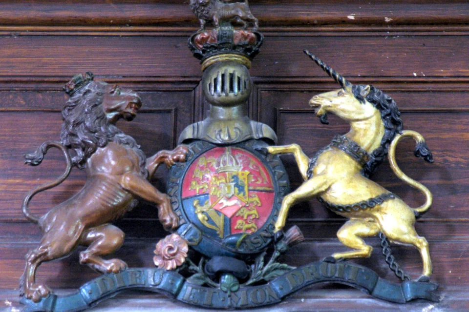 Image of a wood carved Royal Arm depicting a unicorn and a lion