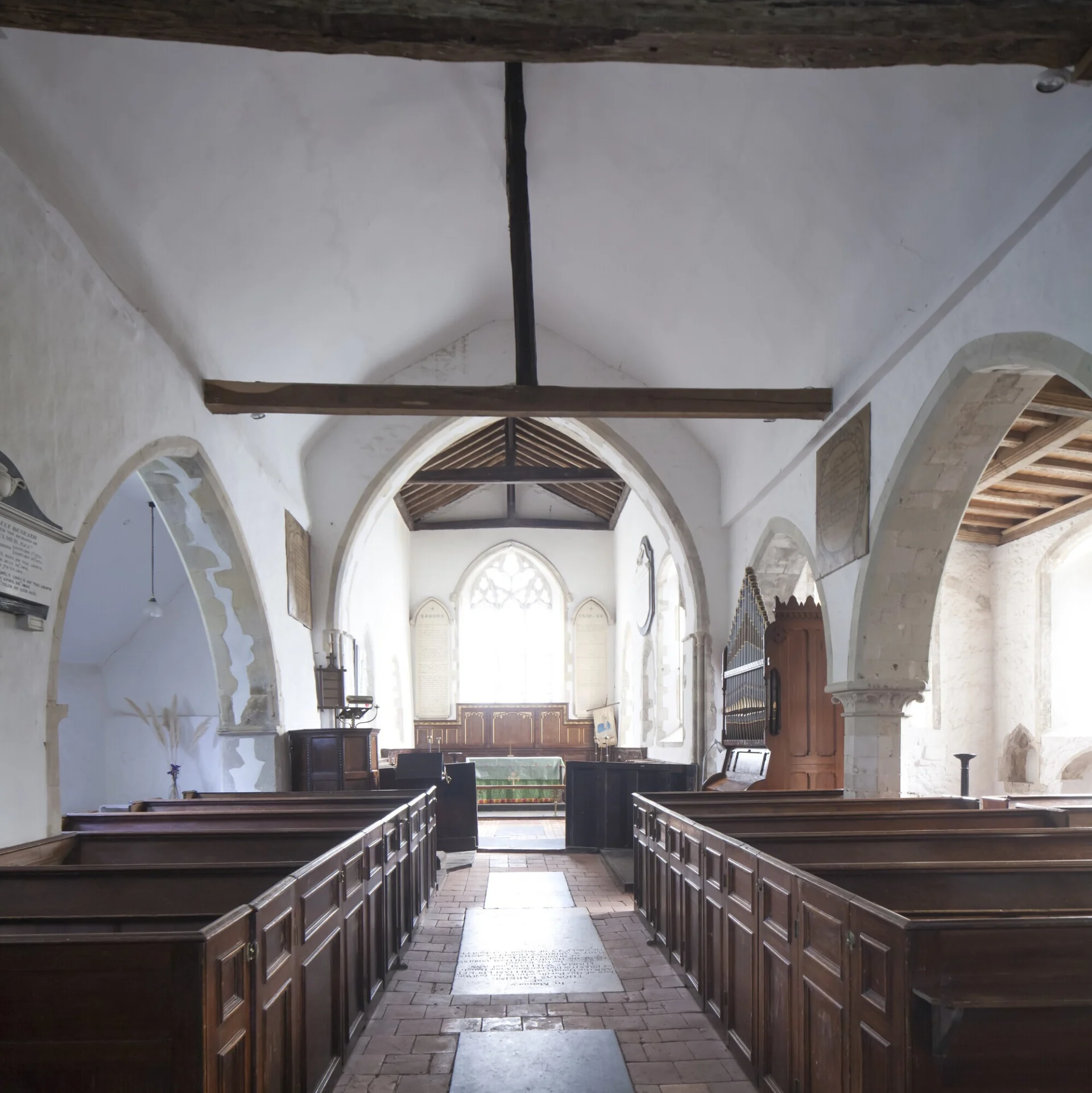 View of the light and airy interior with its stone arches and wood pews