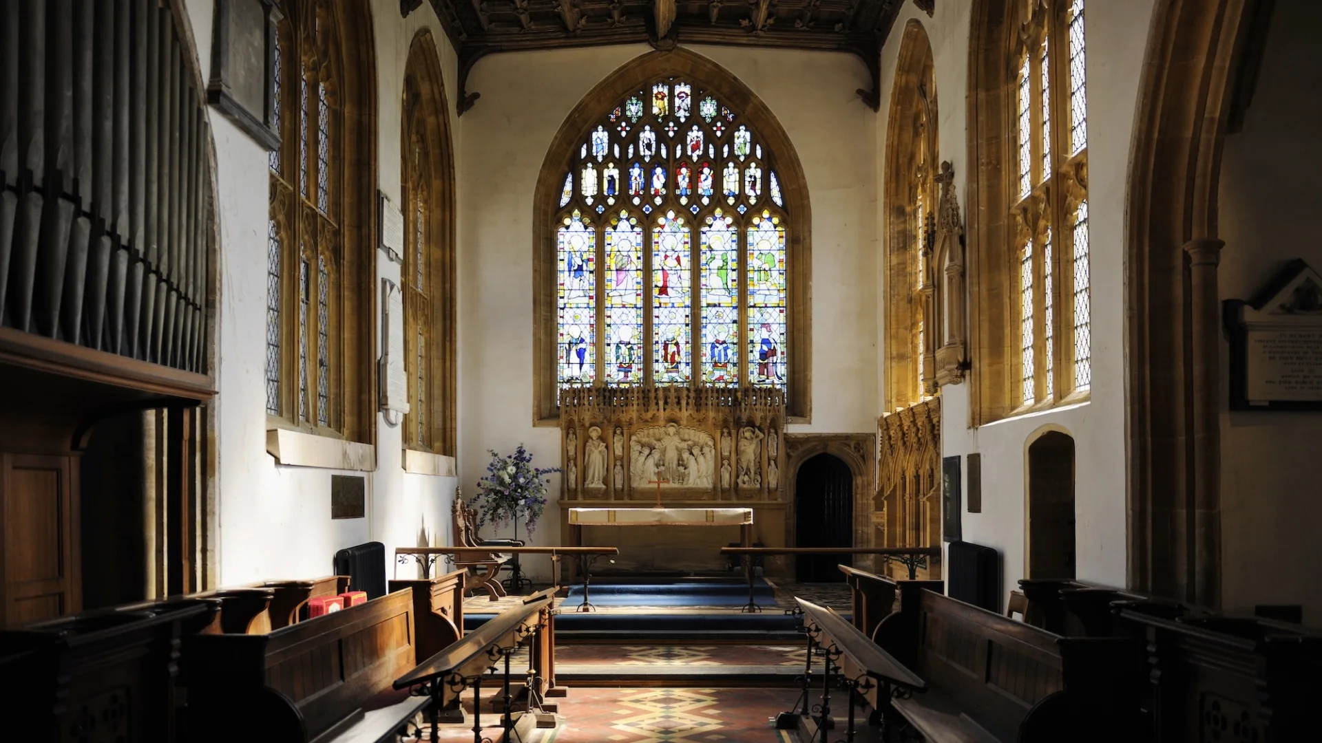 interior showing enormous stained glass windows along the back and walls of the nave. Also a large organ and highly decorated altar with stone carved jesus and the disciples