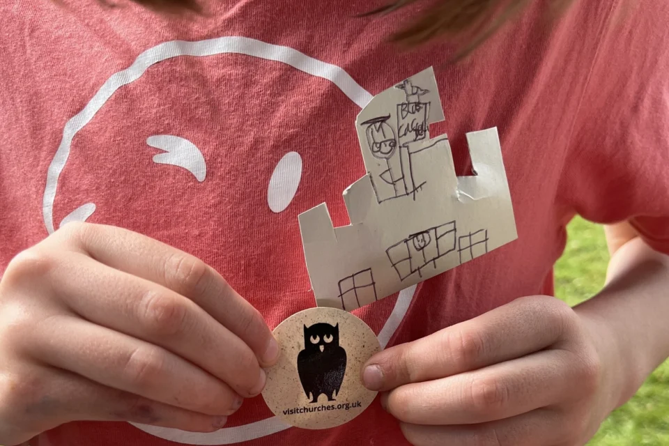 Shows a worn t shirt with a owl badge and hand drawn castle badge