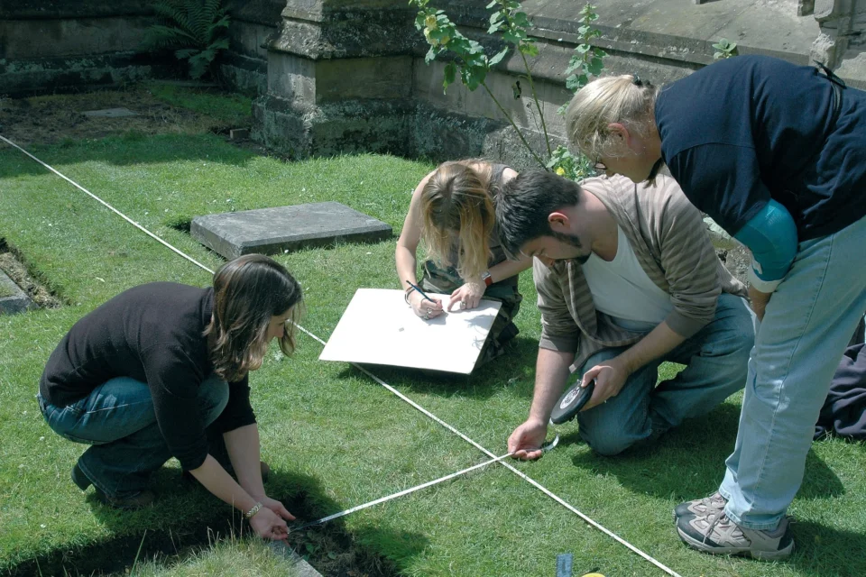 4 people bent over the lawn measuring out the area