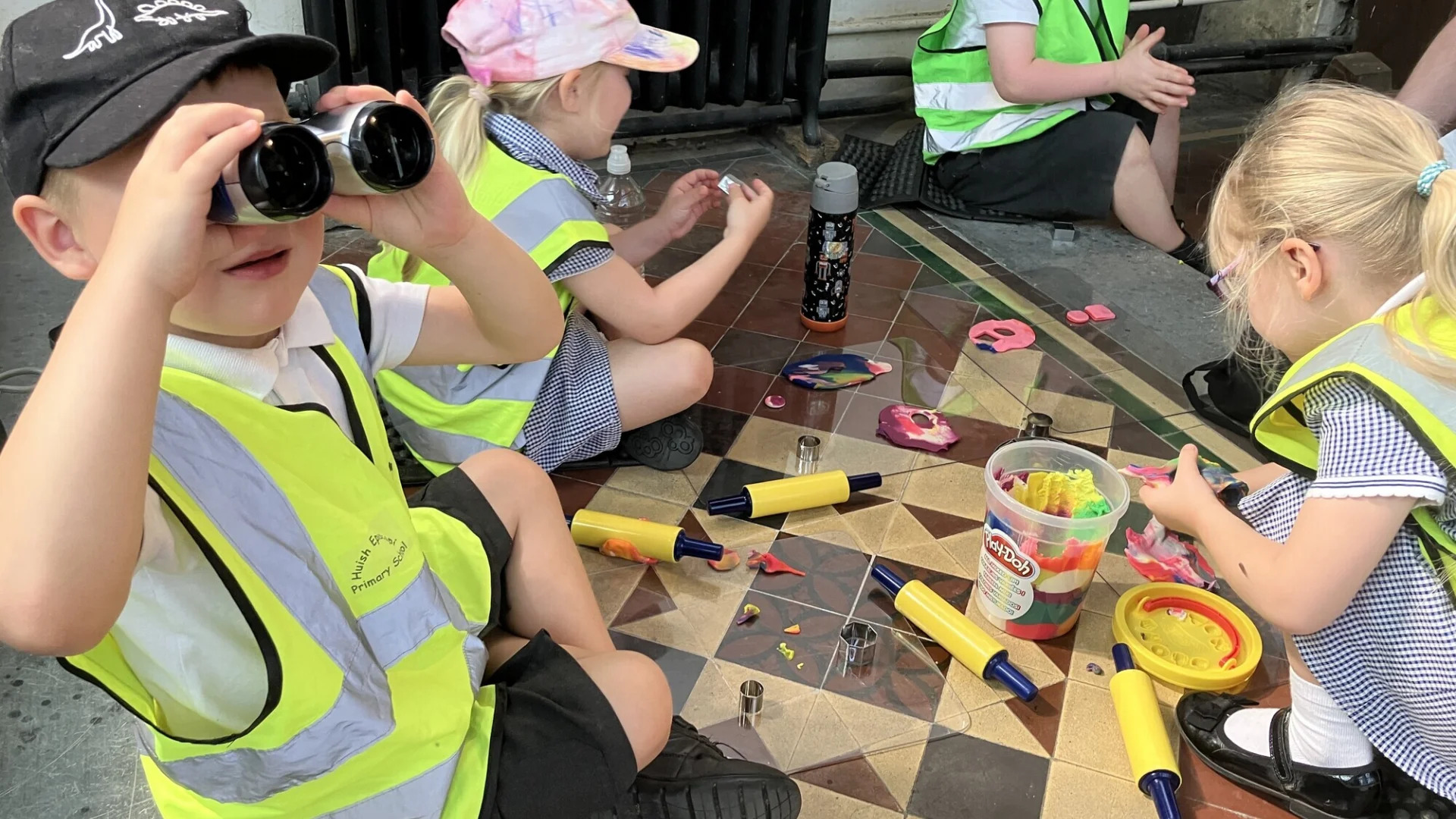 children sit on the church floor playing with play dough and with binoculars