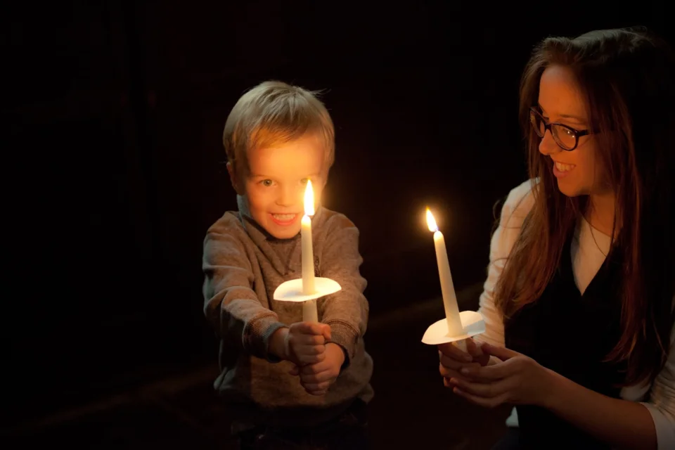 mum and son hold up candles in the dark