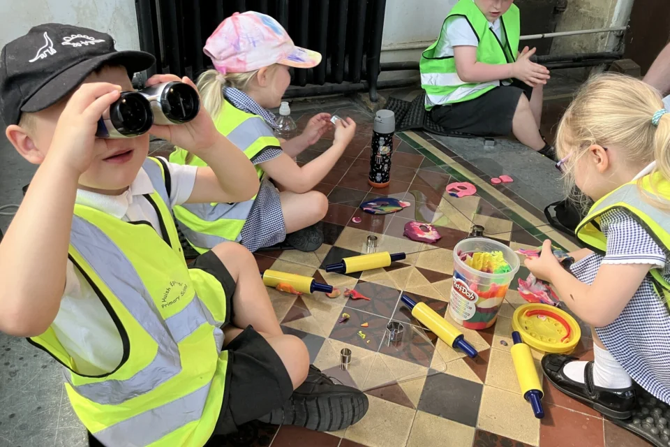 children sit on the church floor playing with play dough and with binoculars