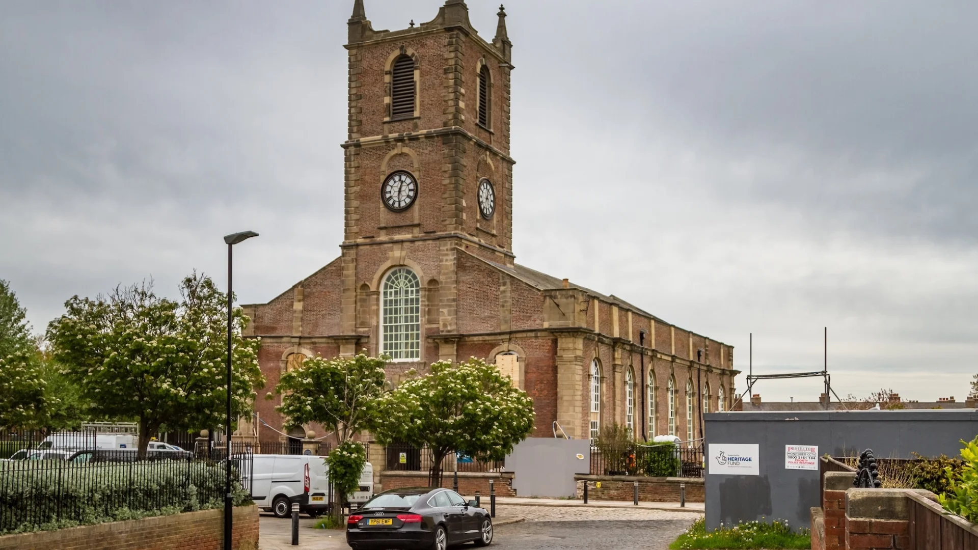handsome brick and stone church exterior surrounded by roads with cars around