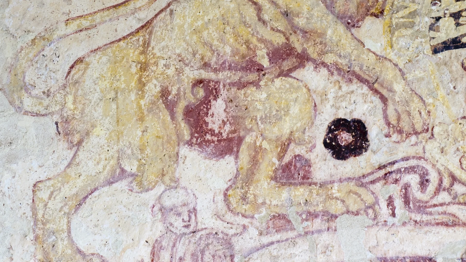 wall painting of lion showing edge of the royal coat of arms overlaying a medieval wall painting of a man in red