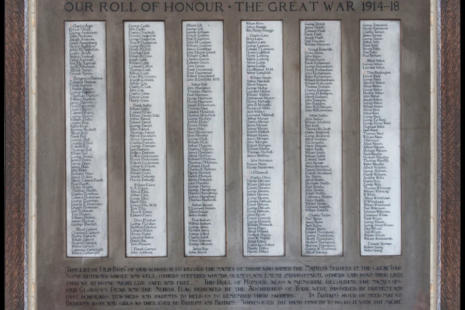 Role of Honour with list of names of pupils  who died, became injured or were Prisoners of War in the Great War. There are hundreds of names in columns on the white background. These columns are then surrounded by a dark brown backdrop.