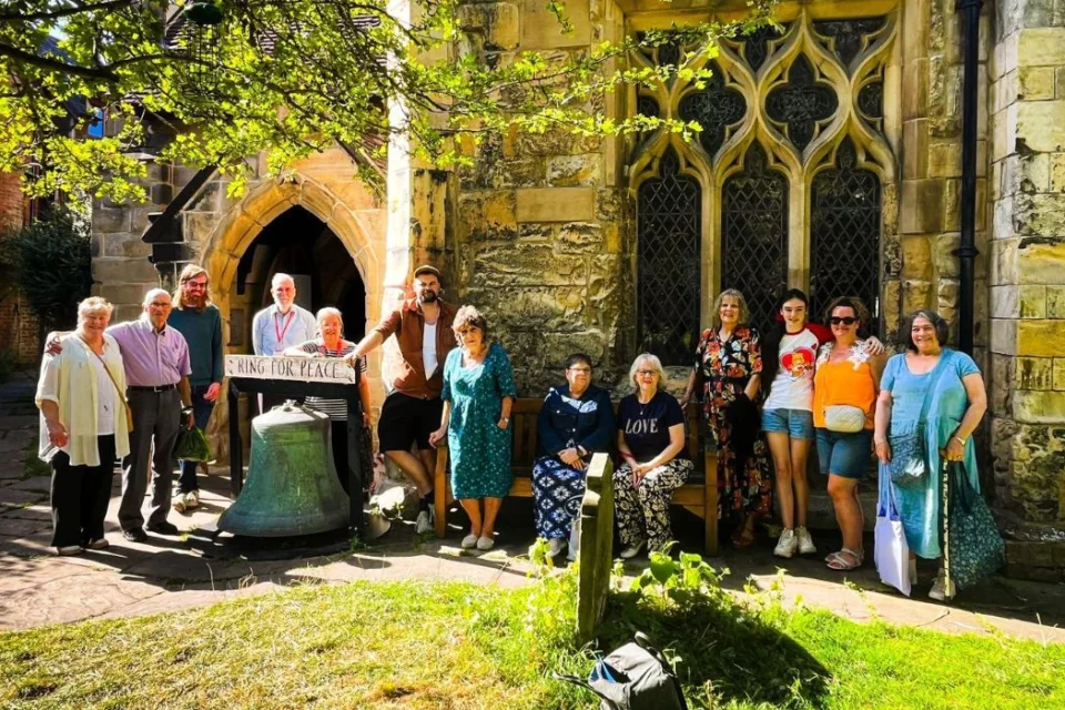 group of people standing in front of the doors and carved, clear-glass windows of Holy Trinity Church