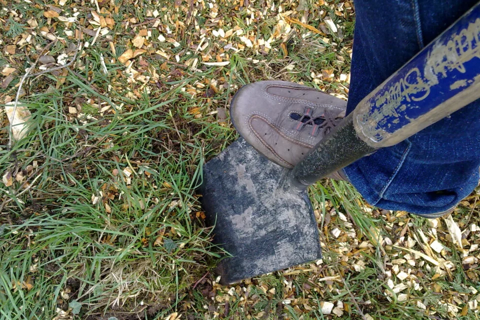 a shovel being pressed down by someone's foot into the ground.